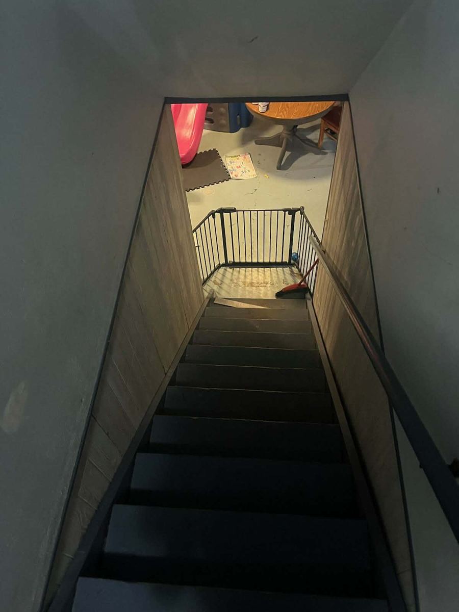 Dark basement stairwell with wood panelling before the rebuild